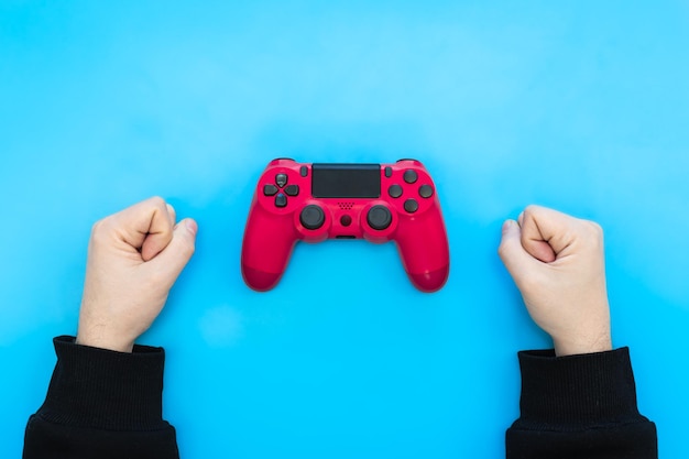 Pink gamepad and male hands on a blue background the concept of winning losing flat lay