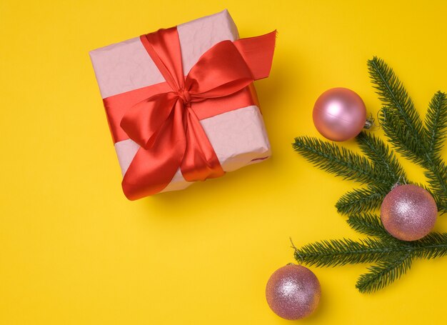 Pink gift box tied with ribbon on a gray background, top view. Festive backdrop