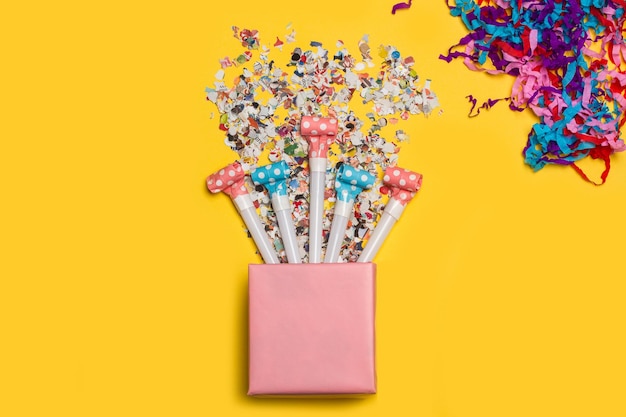 A pink gift box with confetti on a yellow background