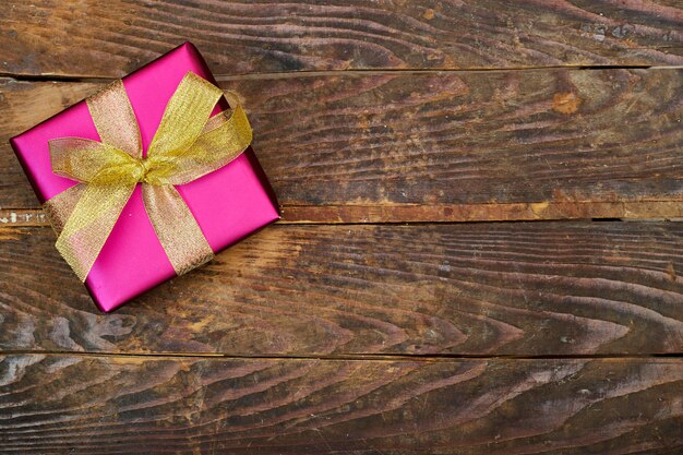 pink gift box with golden ribbon on wood table flat lay