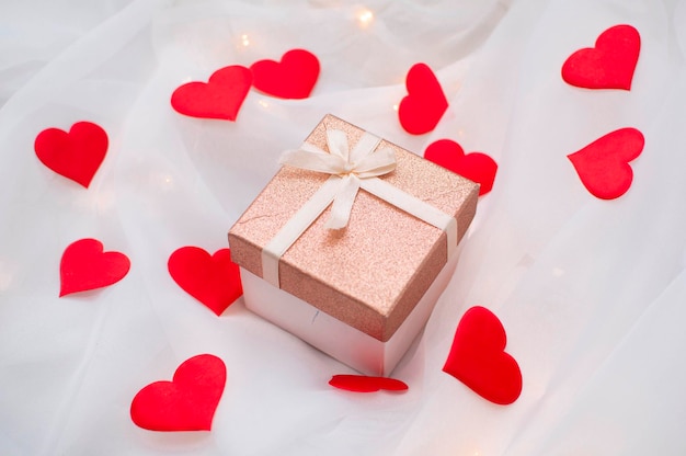 Pink gift box with ribbon bow on white background with hearts. Valentine's day surprise, birthday concept. Space for text. Background with gift and hearts with free space for text. Mother Day concept.