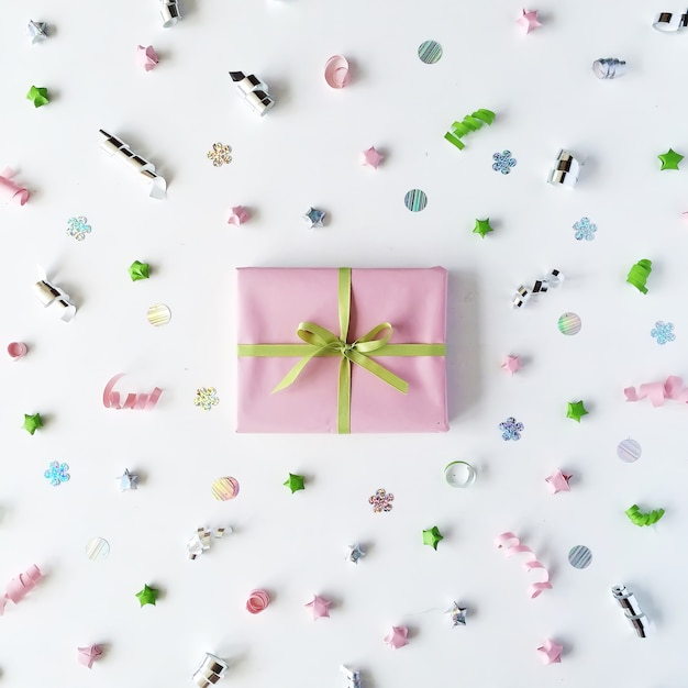 Розовая подарочная коробка с лентой и бантом на белом, украшенная мишурой