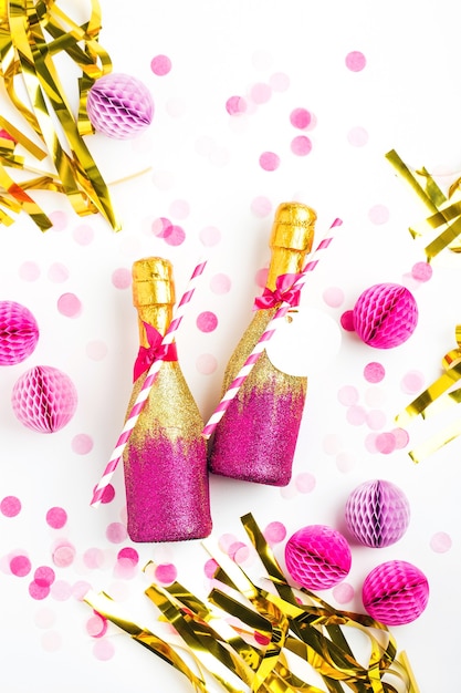 Pink and Gold Mini bottles of champagne with confetti and tinsel. Flat lay. New year celebration or wedding concept theme