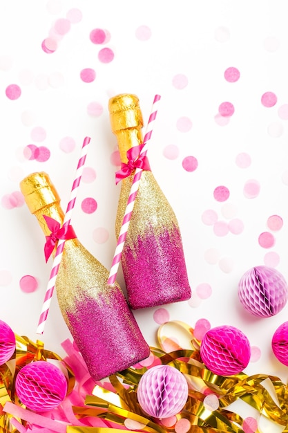 Photo pink and gold mini bottles of champagne with confetti and tinsel. flat lay.