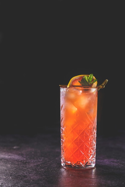 Pink grapefruit mezcal paloma cocktail in highball glass on dark elegant background