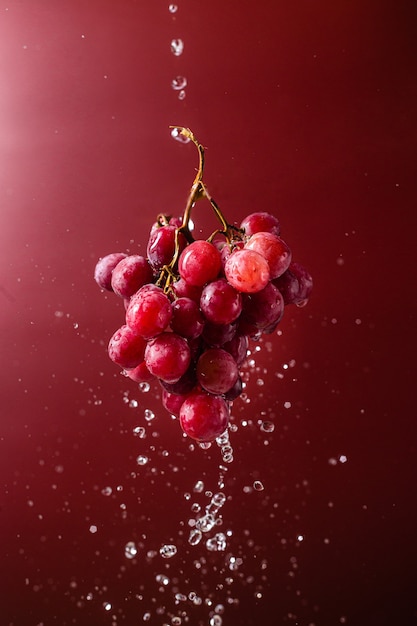 Uva rosa su sfondo rosa con spruzzi d'acqua