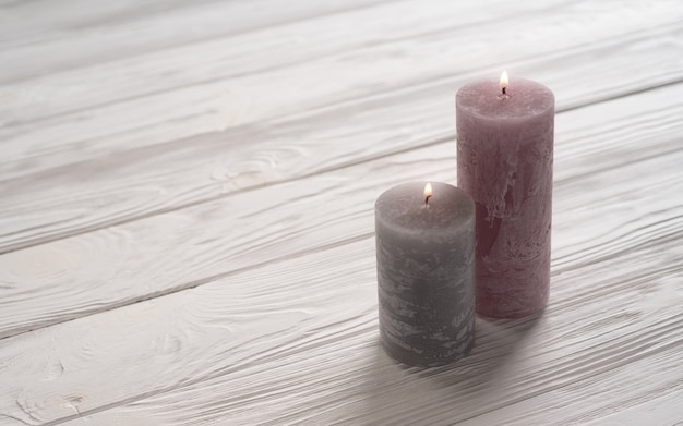 Pink and gray candles on white wooden table