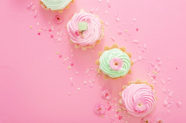 Cupcakes rosa e verdi con fiori di primavera su sfondo rosa