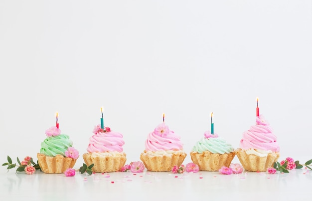 Pink and green cupcakes with spring flowers on white background