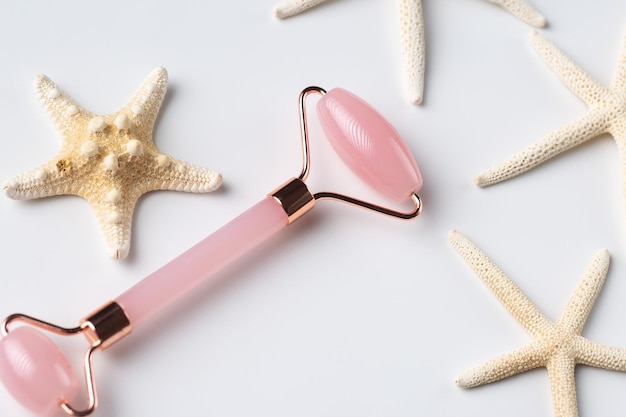 Pink Gua Sha massage tool on a white background closeup Rose Quartz jade roller Facial composition with starfish