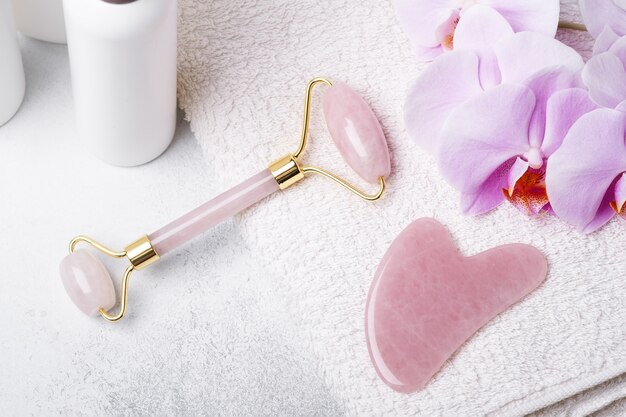 Pink ha massager and face roller on stone background. anti age,\
lifting and toning treatment at home