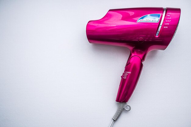 Pink hair dryer and white background