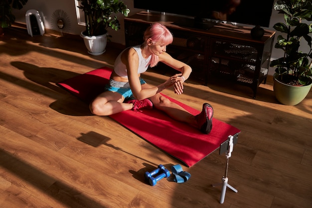 Pink haired woman checks time on smartwatch at training on floor