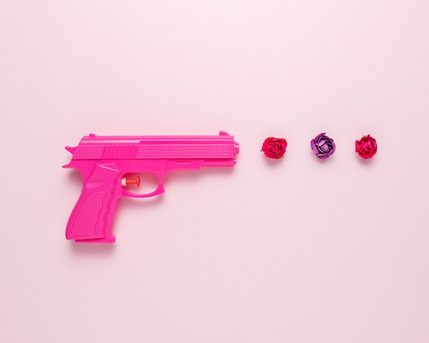 Pink handgun on pink pastel background with flowers