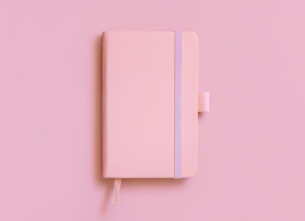 Pink hardcover notebook on light pink top view. Textbook cover mockup, planner cover with place fot text. Educational, business and organizing concept