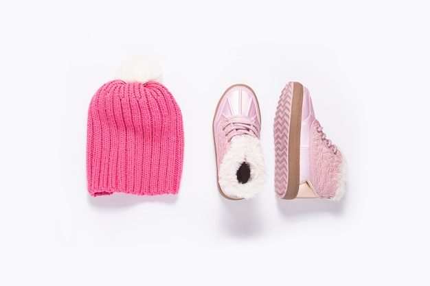 Pink hat and boots for a girl on a white background. Top view, flat lay.