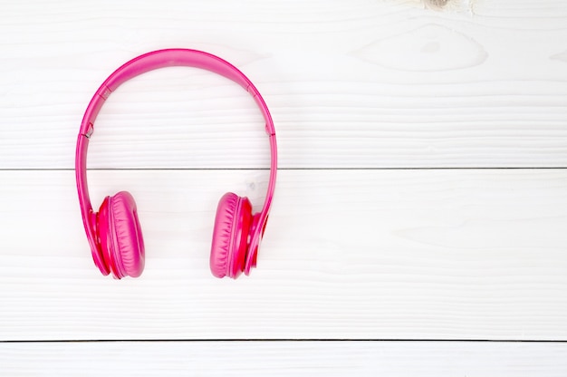 Photo pink headphones on a white wooden table