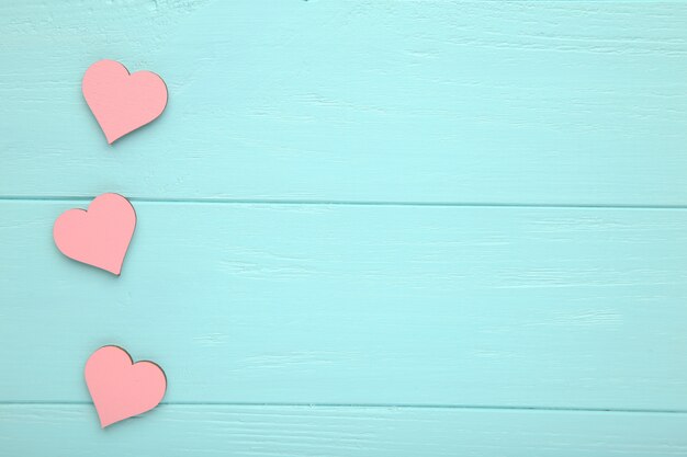 Pink hearts on a blue wooden background.