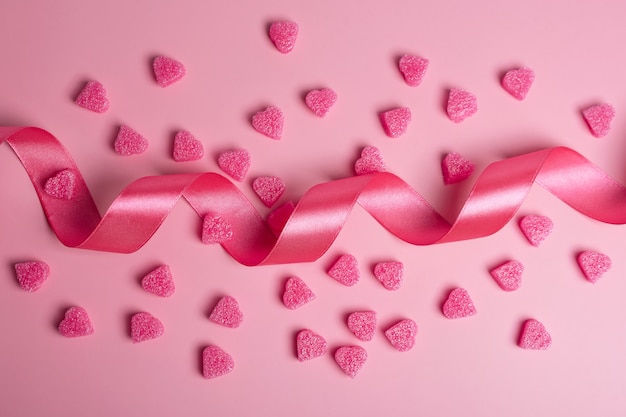 Photo pink hearts on pastel pink background with ribbon. romantic background for valentine's day