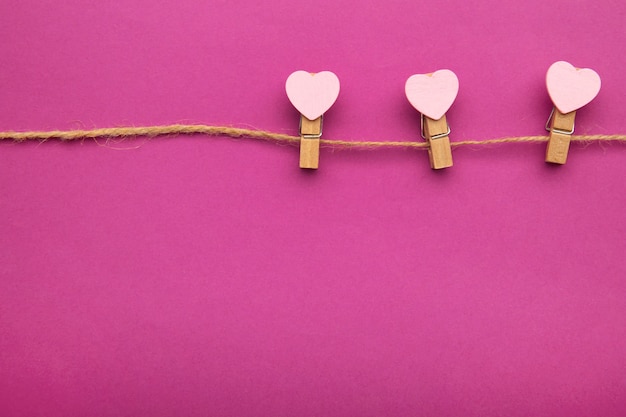 Pink hearts on rope with clothespins, on pink