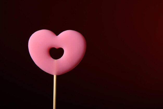 Pink heartshaped lollipop on a dark red background Horizontal banner for Valentines Day