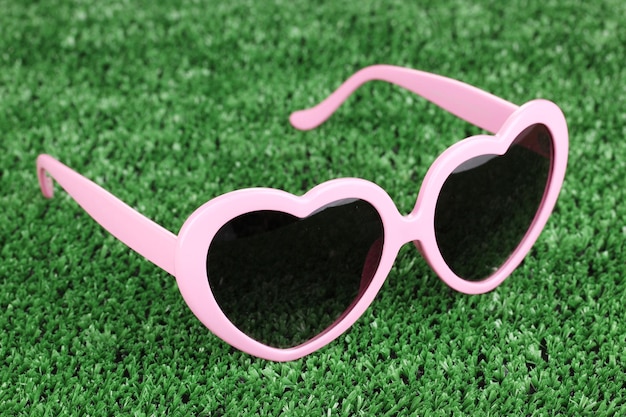 Photo pink heartshaped sunglasses on green grass