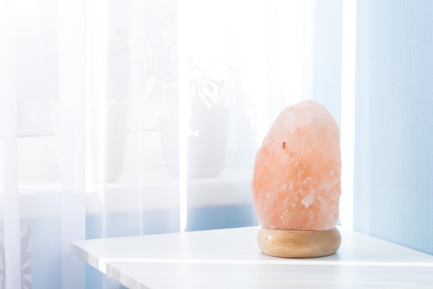 Pink himalayan rock lamp on white table in sunny day