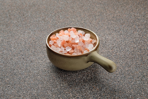 Pink Himalayan salt in a ceramic bowl on stone surface