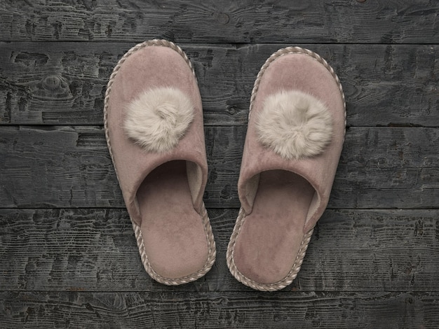 Pink homemade women's slippers on a wooden background The concept of home shoes