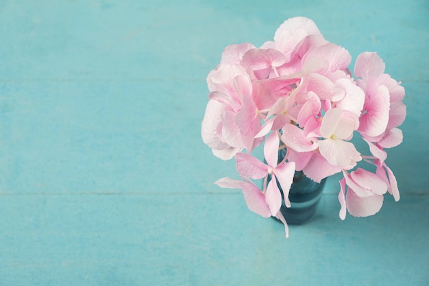 青い木製のテーブルの上に花瓶のピンクのアジサイの花