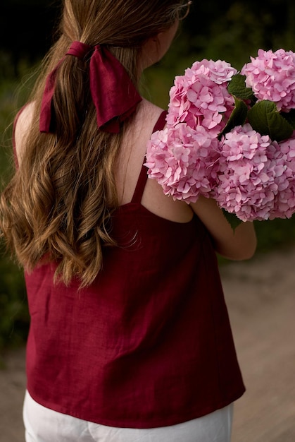 Foto ortensia rosa. la ragazza tiene un mazzo di ortensie. ragazza con fiori