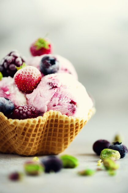 Pink ice cream with berries, strawberries, blueberries, raspberries, pistachios. 