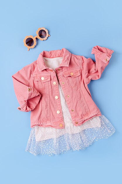사진 핑크 자켓과 귀여운 드레스. 어린이 복장의 패션 세트입니다.