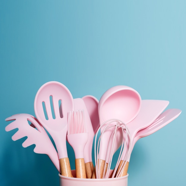 Utensili da cucina rosa sul concetto blu e domestico della decorazione degli strumenti della cucina, accessori di gomma in contenitore. tema ristorante, cucina, cucina, cucina. spatole e spazzole in silicone