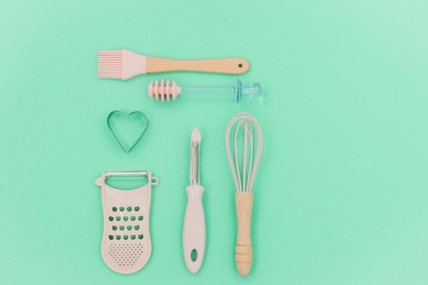 pink kitchen utensils. Greater, whisk and iron cooking form. Top view