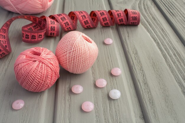 Photo pink knitting and pink centimeter on the grey wooden background