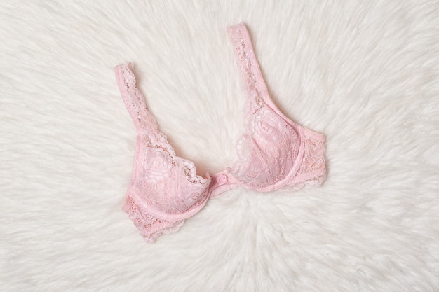 Pink lace bra on white fur. Flat lay. Fashion lingerie concept.