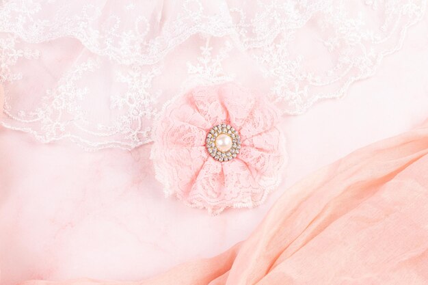 Pink lace flower with a pearl on a pink background