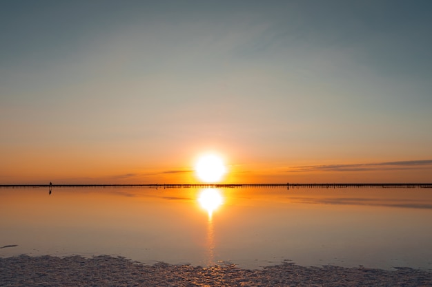 Pink lake and sandy beach with a sea bay under a blue sky with clouds