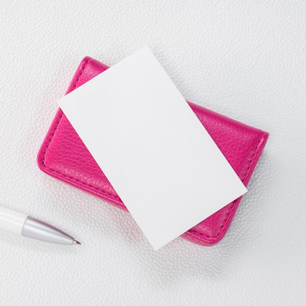 ピンクの革カードホルダーと合成の白い背景の上の白いカード。