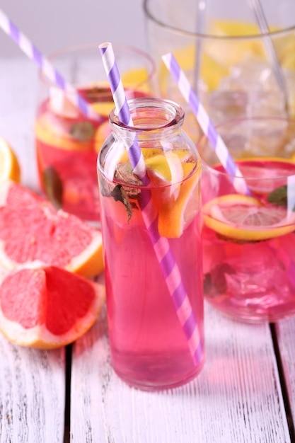 Pink lemonade in glasses and bottle on table closeup