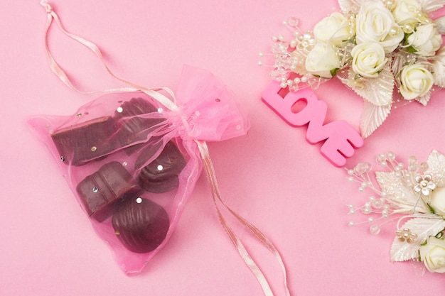 Pink letters love chocolate candies and hearts on a pink surface