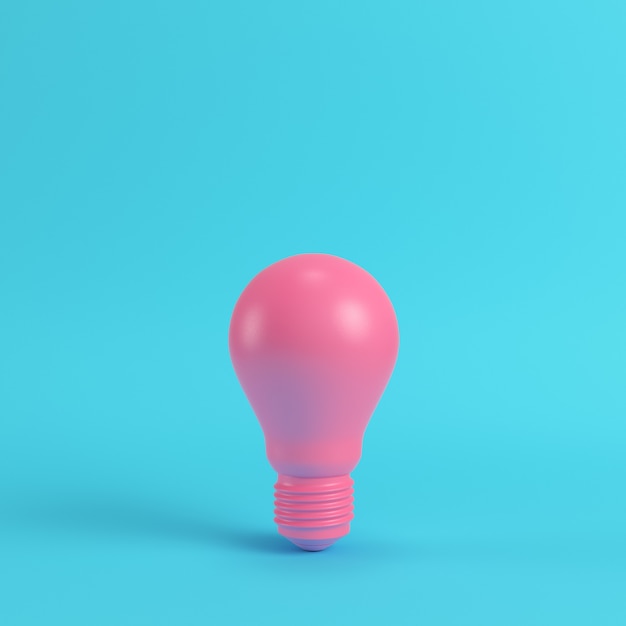 Photo pink light bulb on bright blue background