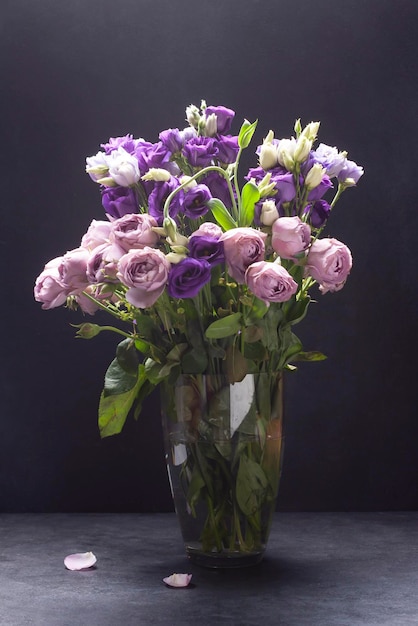 pink and lilac roses in a glass vase dark photo