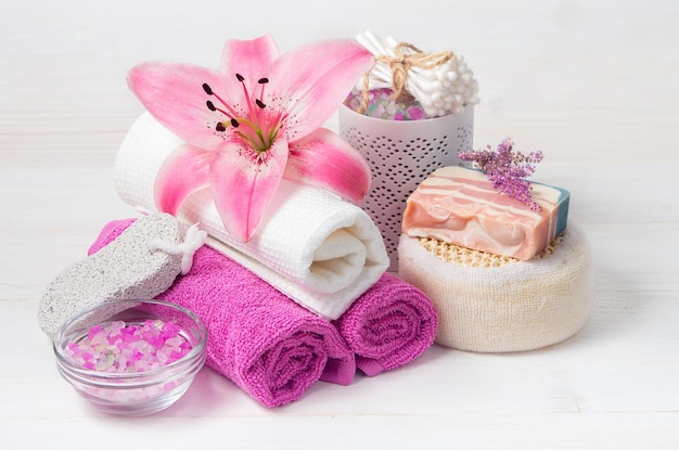 写真 ピンクのユリの花の塩タオル靴と白い木製の背景にスパの手順のためのオブジェクトボディケアのための自然化粧品
