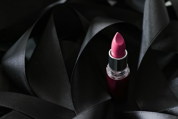 黒のシルクの背景にピンクの口紅高級メイクと美容化粧品