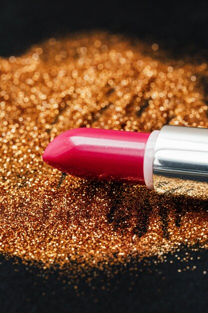 Pink lipstick lies on golden glitter