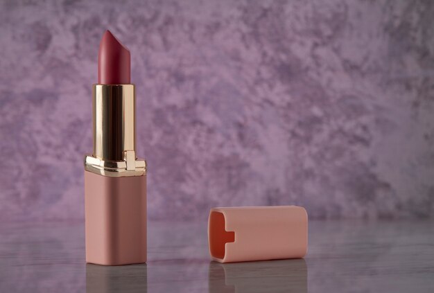 Pink lipstick on a marble surface with a pink background and room for text