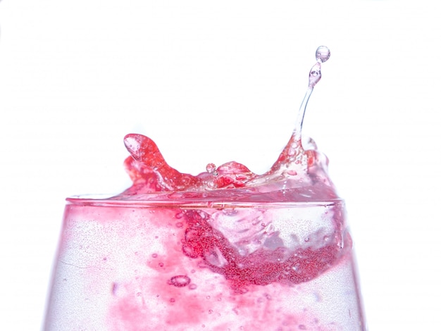 Розовая жидкость падает на стакан