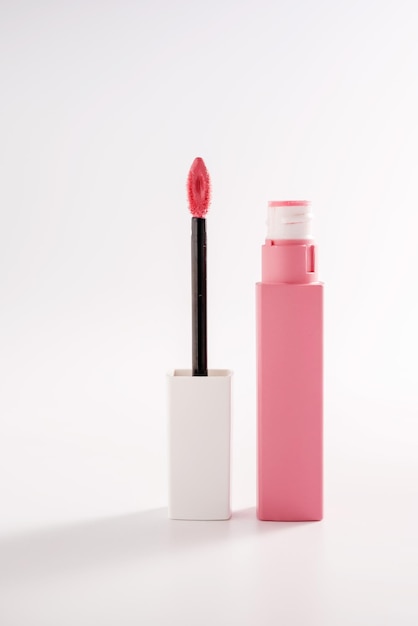 Pink liquid lipstick and applicator brush with open tube Makeup cosmetic product Bright background